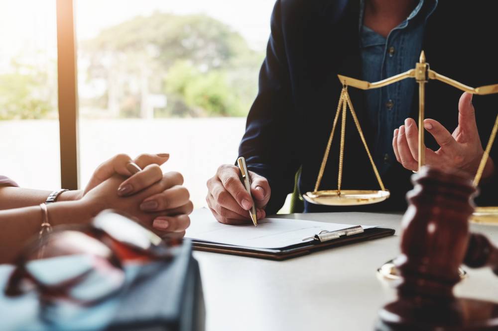 Mains feuilletant une convention d'honoraires d'avocat papier avec calculatrice sur un bureau