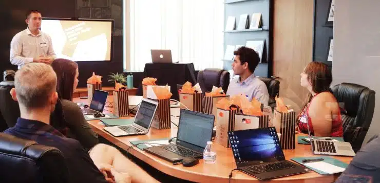 man standing in front of people sitting beside table with laptop computers